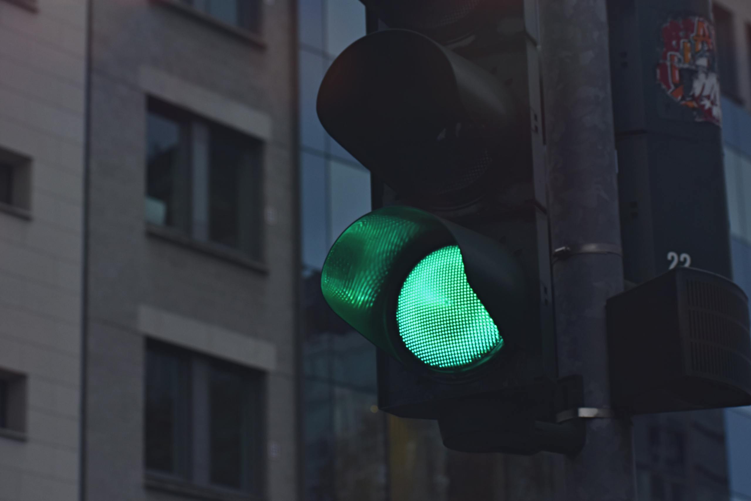 A close-up of a green traffic light in a city street scene.
