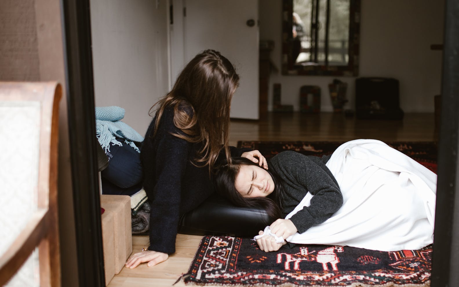 A woman comforts another during an emotional moment indoors, evoking themes of empathy and support.